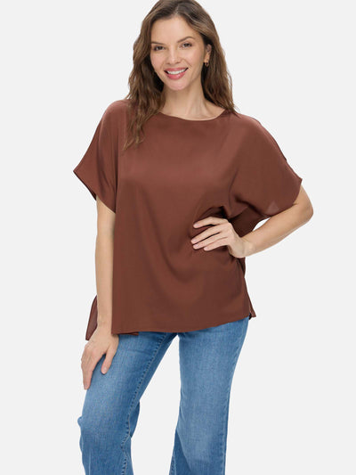 Woman wearing a brown silk top and blue jeans on a white background