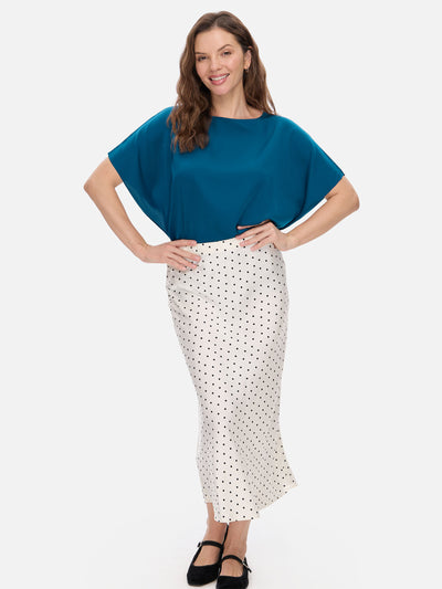 Woman wearing a blue silk top and white polka dot skirt on a white background