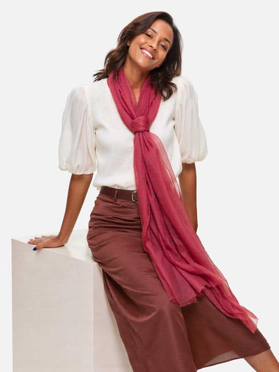 Woman wearing a white blouse and brown skirt with a pink scarf on a white background