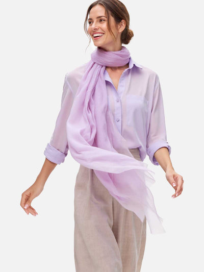 Woman wearing a light purple scarf and shirt on a white background