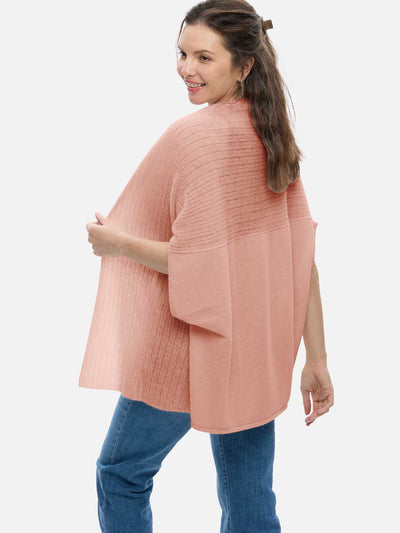 Woman wearing a pink cashmere vest and blue jeans on a white background