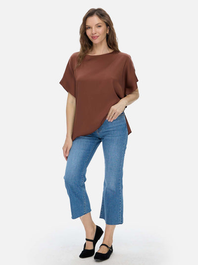 Woman wearing a brown silk top and blue jeans on a white background