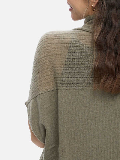 Person wearing a green cashmere vest with a plain background