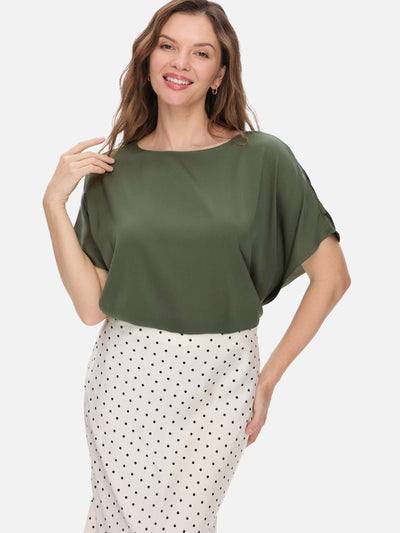 Woman wearing a green silk top and polka dot skirt on a white background