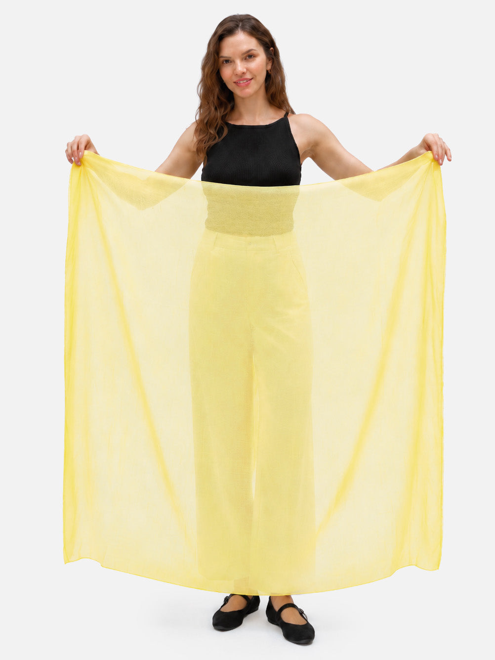 Woman holding a yellow Featherlight Square Cashmere Scarf fully open to show its generous square shape, lightweight weave, and sheer finish.