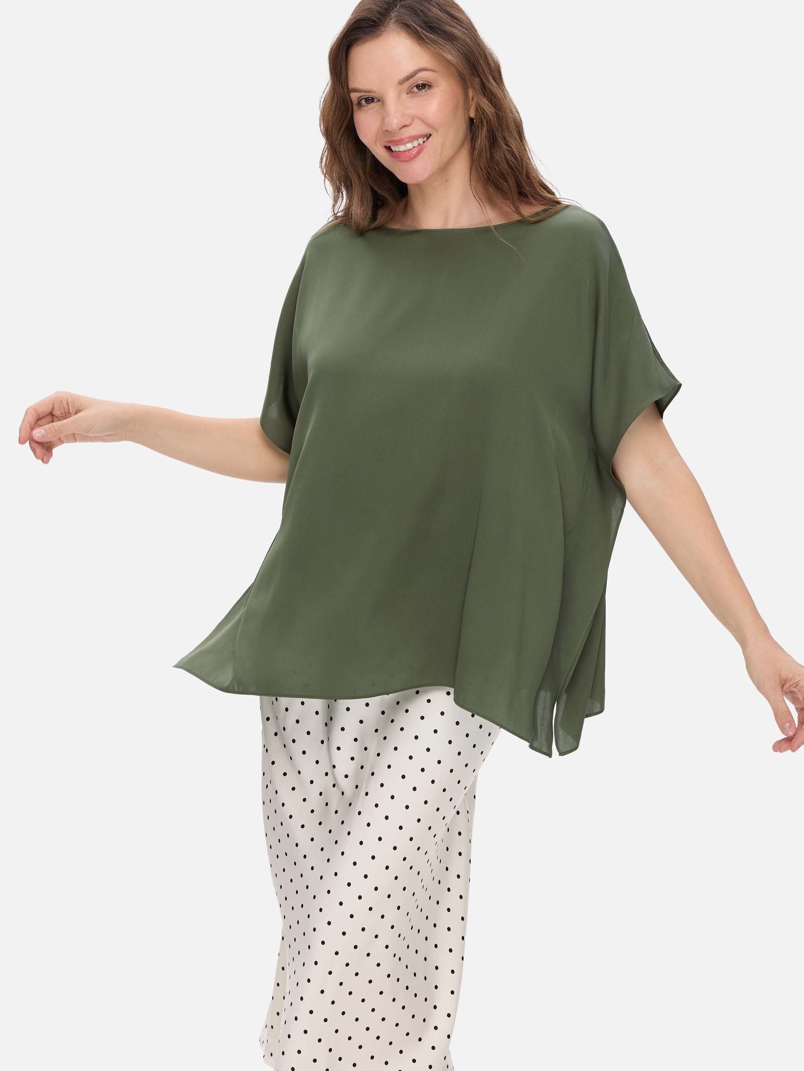 Woman wearing a green silk top and polka dot pants on a white background