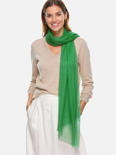 Woman wearing a green scarf and beige sweater on a white background