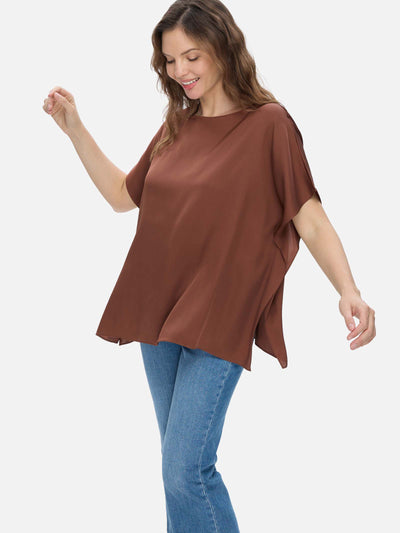 Woman wearing a brown silk top and blue jeans on a white background