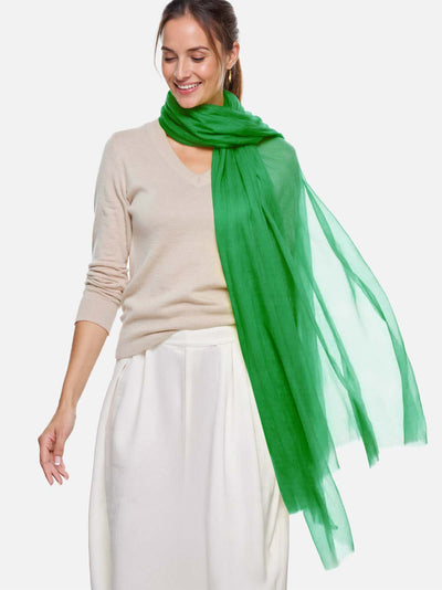 Woman wearing a green scarf and beige sweater on a white background