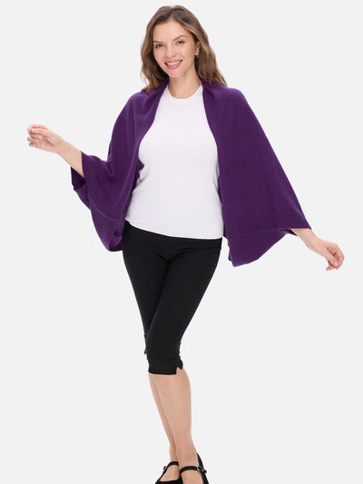 Woman wearing a purple cashmere wrap over a white shirt and black pants on a white background