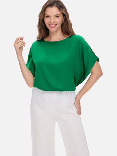 Woman wearing a green silk top and white pants on a white background