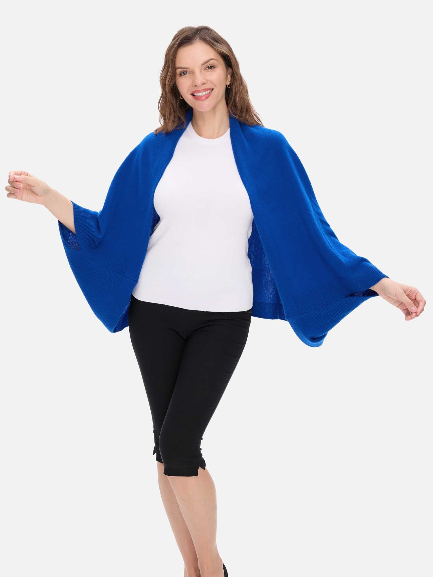 Woman wearing a blue cashmere wrap over a white top and black pants on a white background