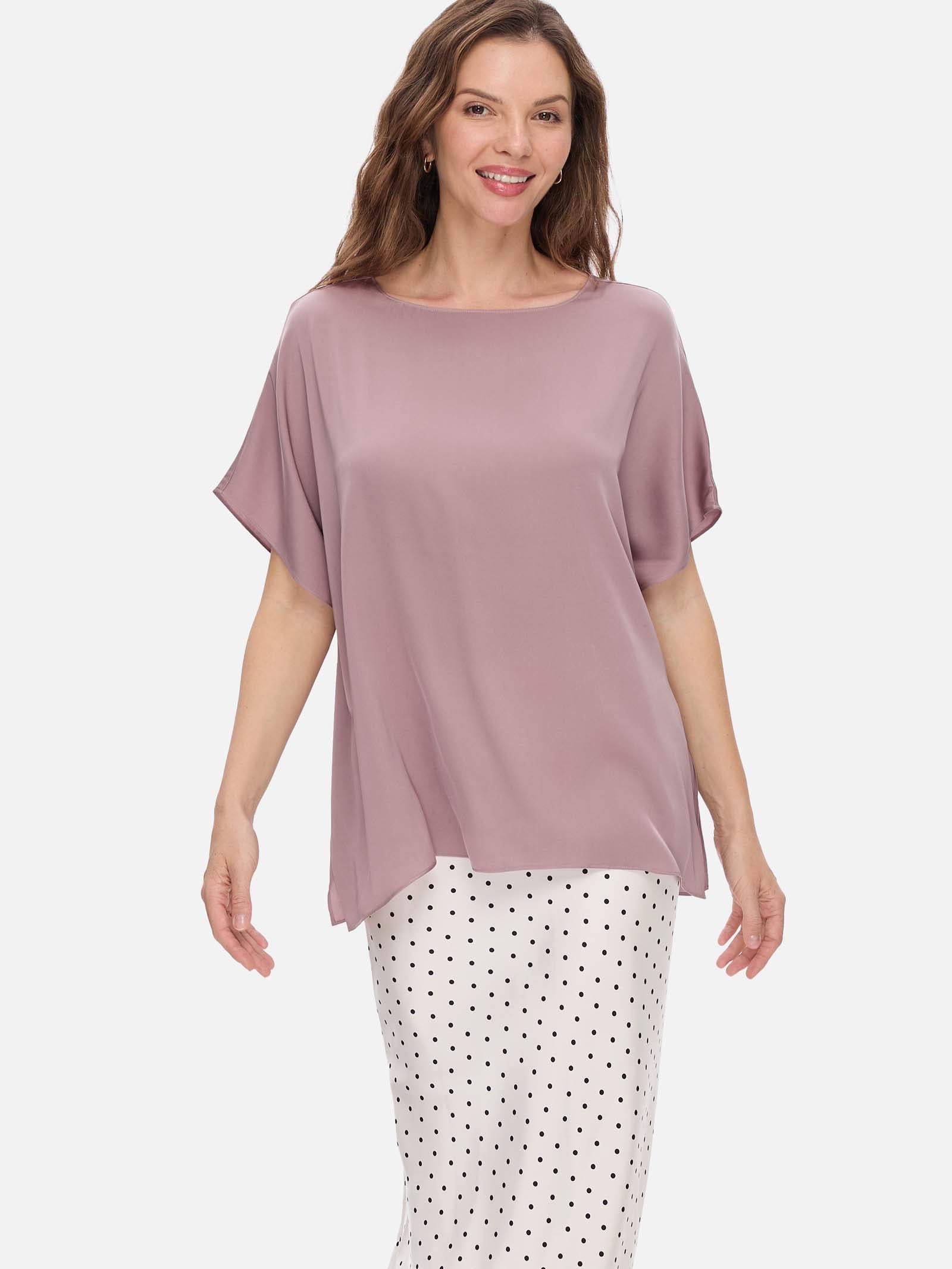 Woman wearing a mauve silk top and polka dot pants on a white background