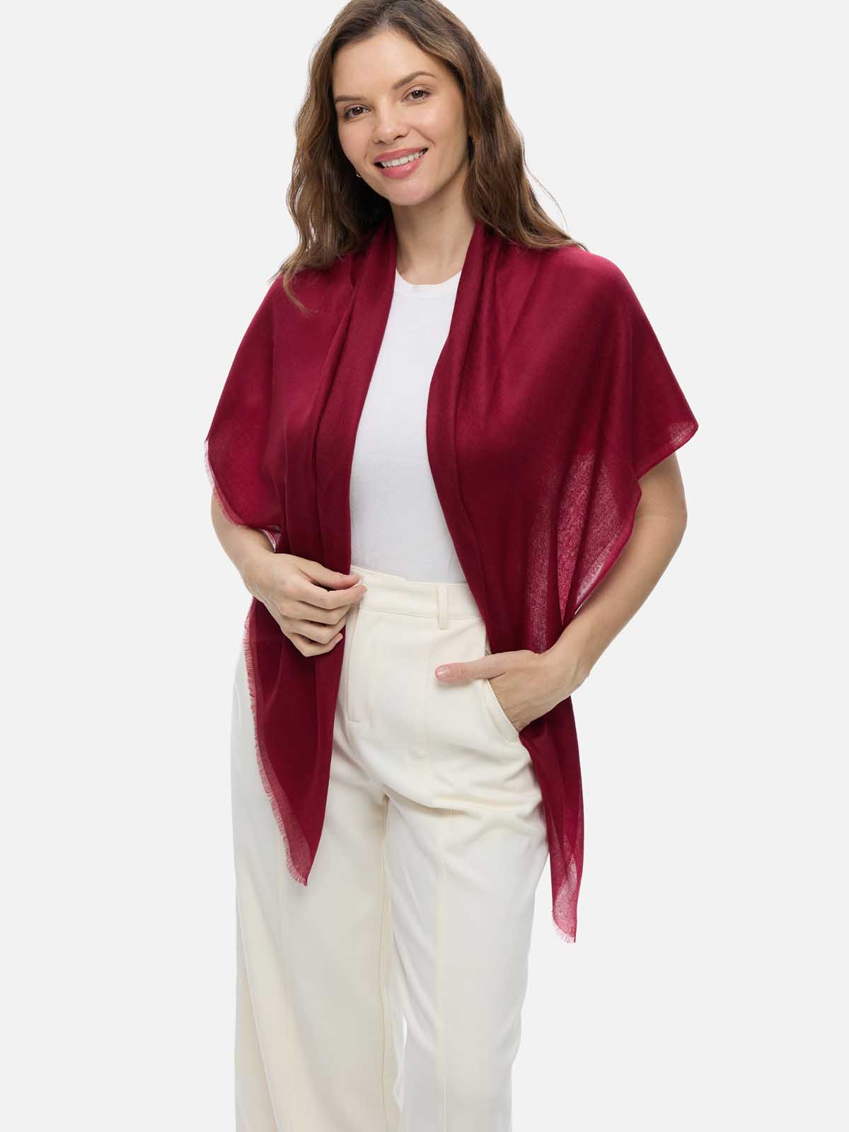 Woman wearing a wine red Ovcio Featherlight Cashmere Scarf over a white top and ivory trousers.