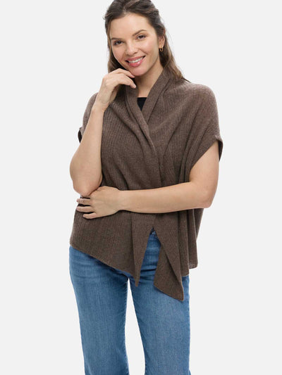 Woman wearing a brown cashmere vest over a black top and blue jeans on a white background