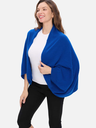 Woman wearing a blue cashmere wrap over a white shirt and black pants on a white background