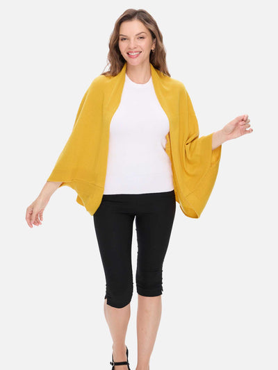 Woman wearing a mustard yellow cashmere wrap over a white top and black pants on a white background