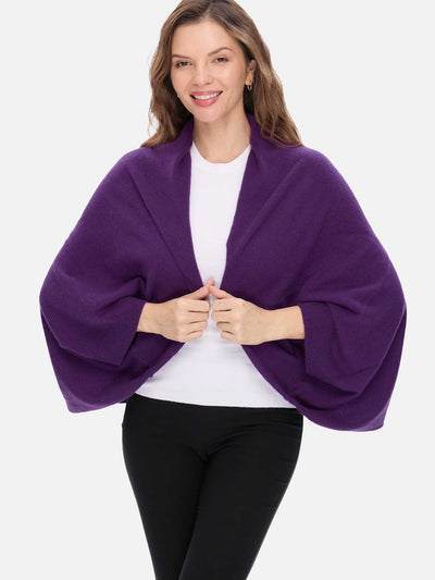 Woman wearing a purple cashmere wrap over a white top and black pants on a white background