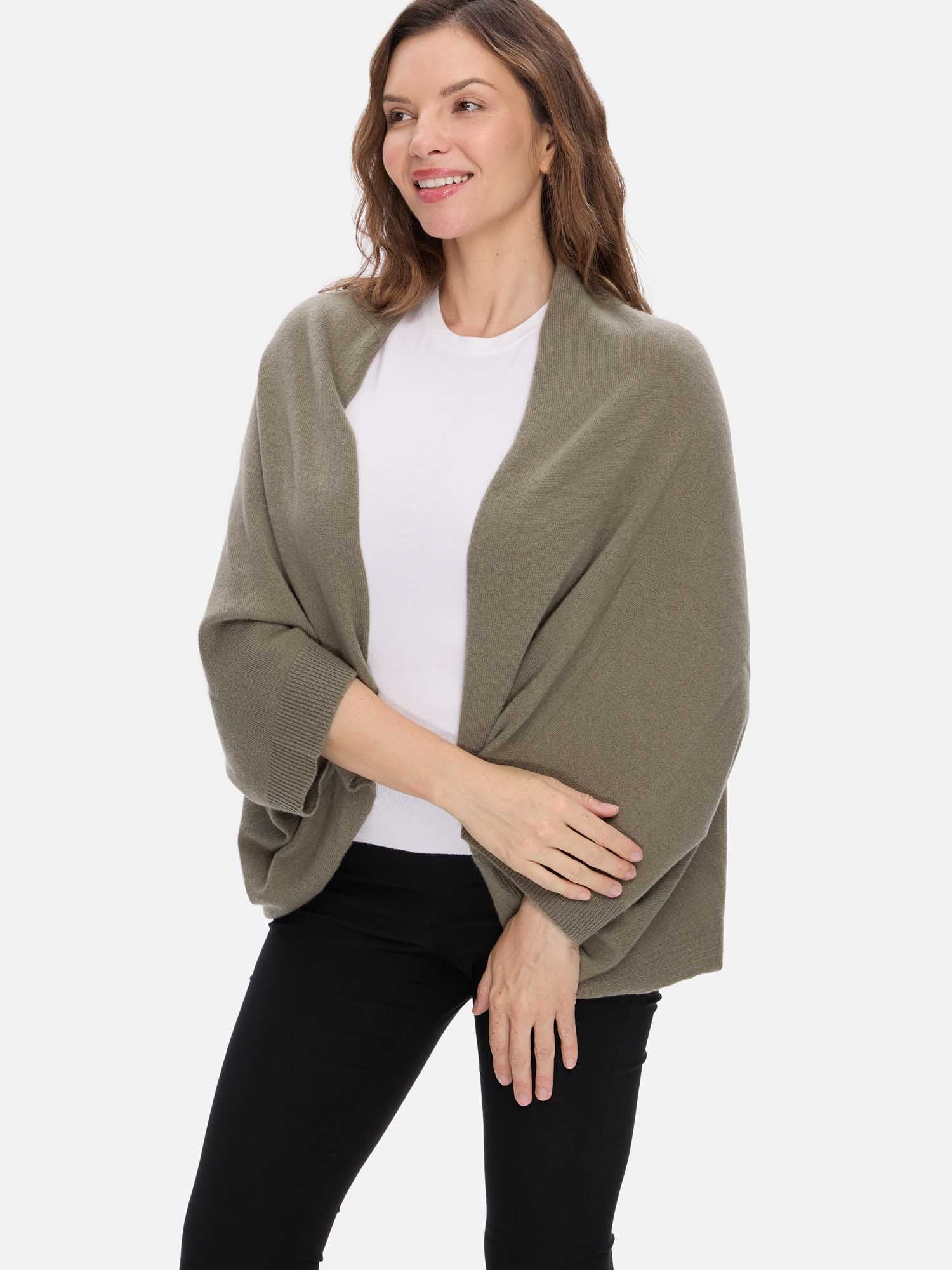 Woman wearing a green cashmere wrap over a white shirt and black pants on a white background