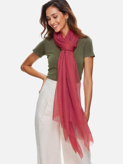 Woman wearing a green shirt, white pants, and a pink scarf on a white background