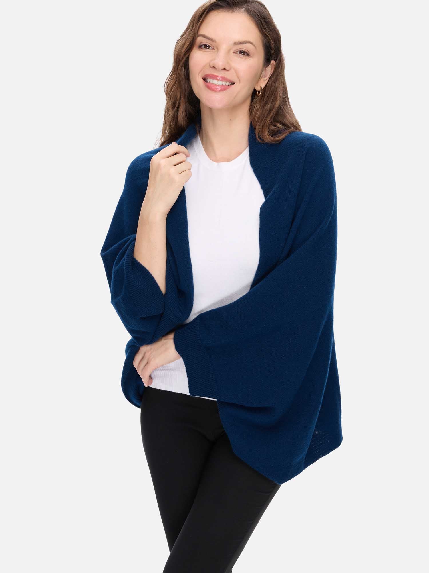 Woman wearing a navy blue cashmere wrap over a white shirt and black pants on a white background
