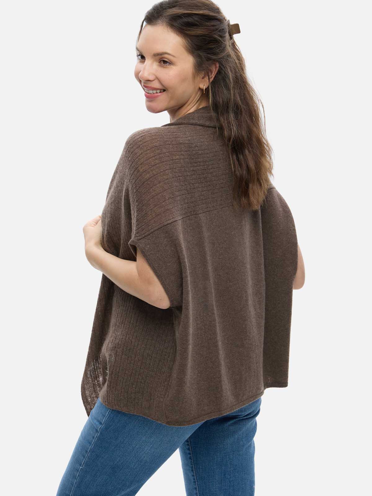 Woman wearing a brown cashmere vest over a blue outfit on a white background