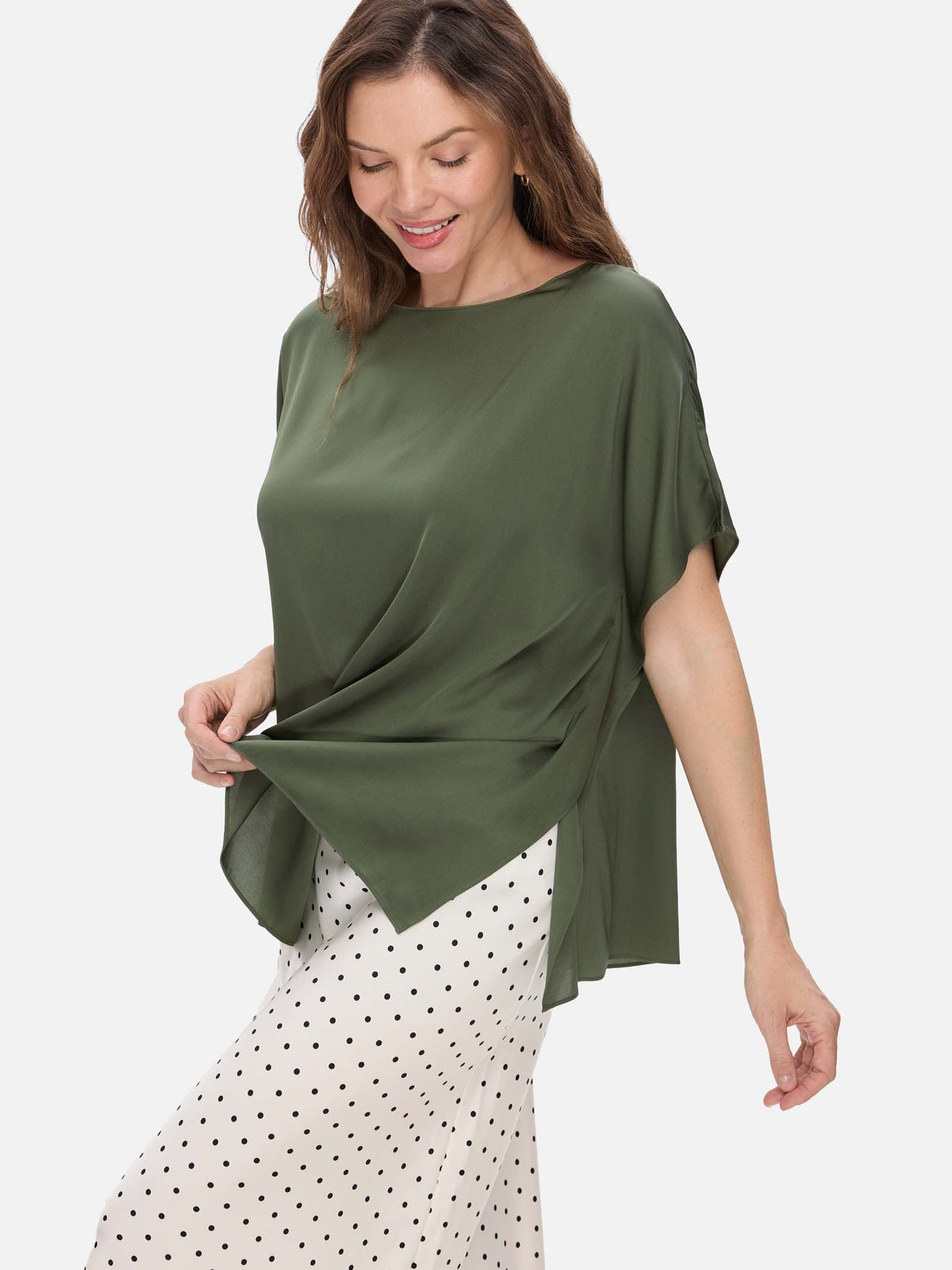 Woman wearing a green silk top and polka dot skirt on a white background