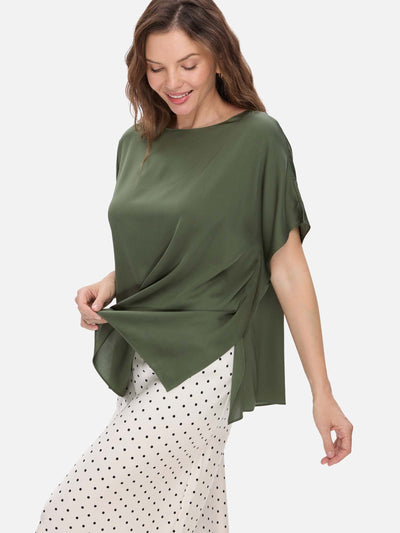 Woman wearing a green silk top and polka dot skirt on a white background