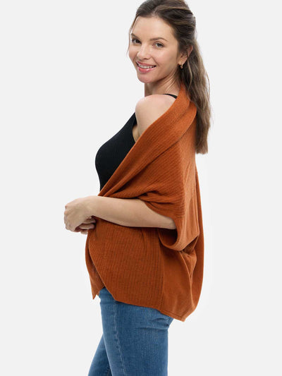 Woman wearing a rust-colored cashmere vest over a black top on a white background