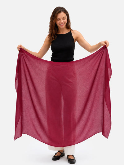 a woman holding the fully-opened featherlight cashmere scarf in wine red color.