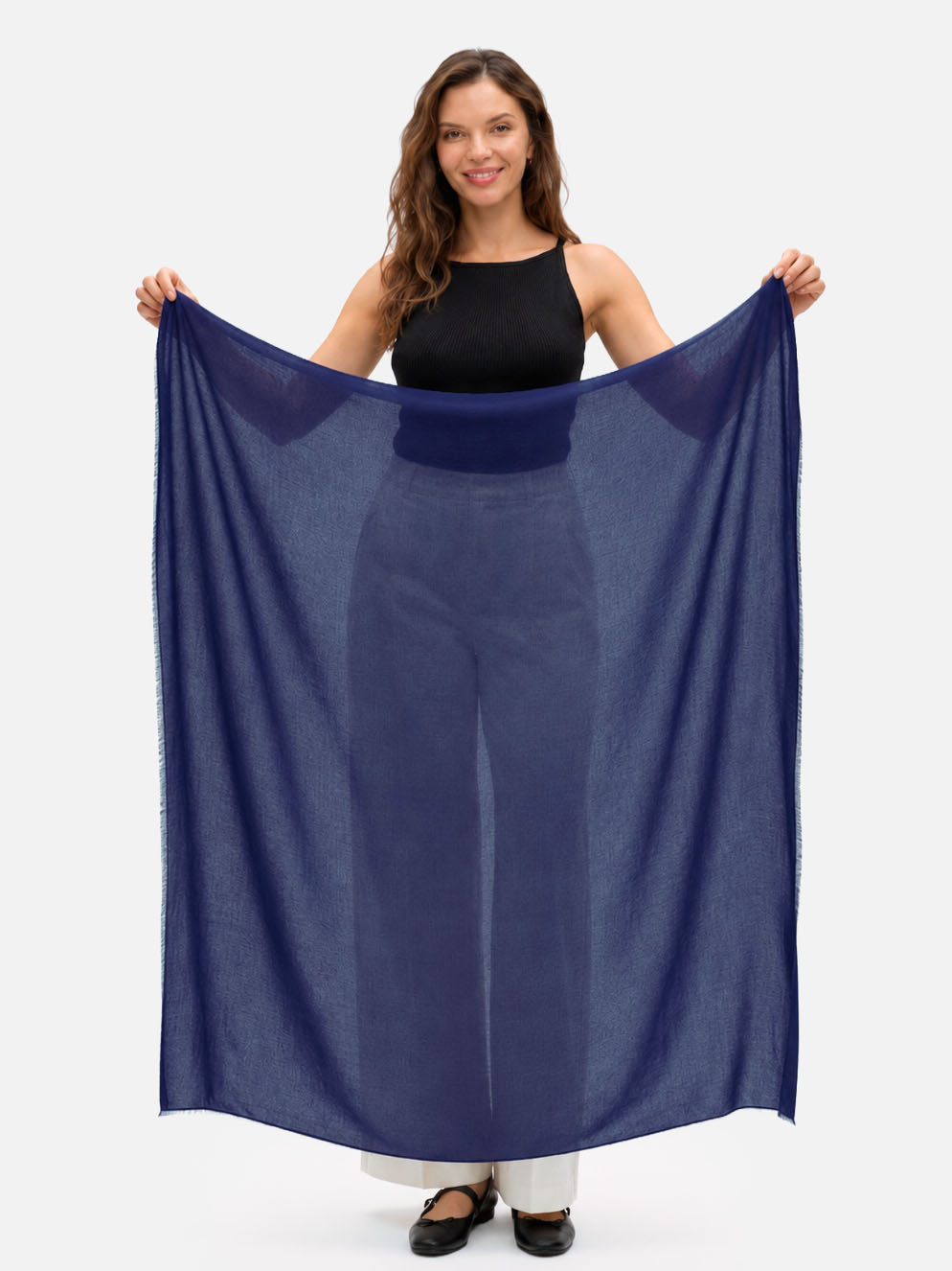 Woman holding a navy blue Featherlight Square Cashmere Scarf fully open to show its generous square shape, lightweight weave, and sheer finish.