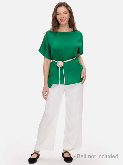 Woman wearing a green silk top and white pants on a white background