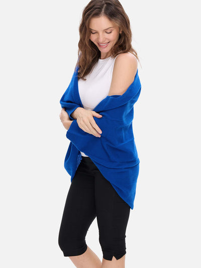 Woman wearing a blue cashmere wrap over a white top and black pants on a white background