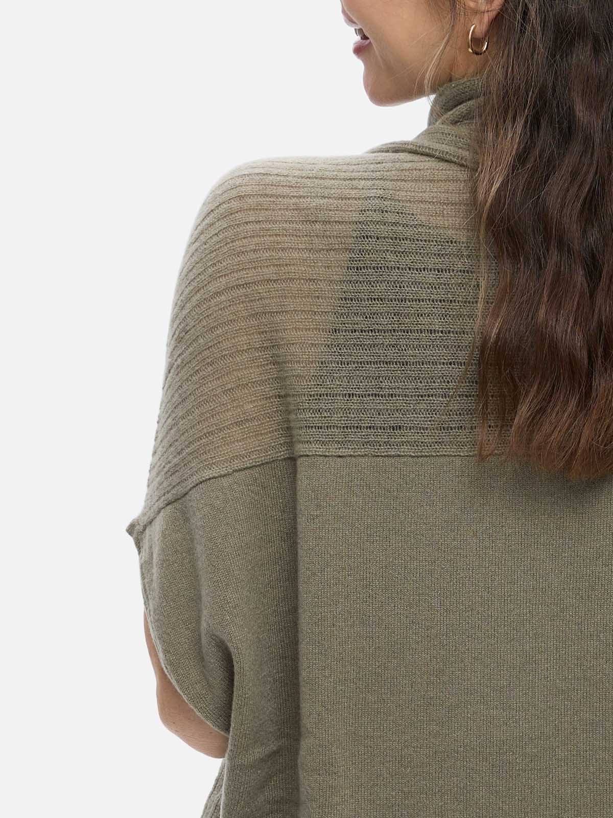 Person wearing a green cashmere vest with a plain background