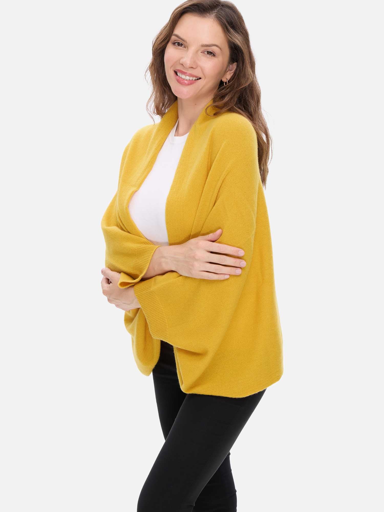 Woman wearing a yellow cashmere wrap over a white top on a white background