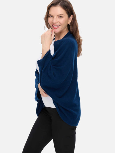 Woman wearing a blue cashmere wrap over a white shirt on a light gray background