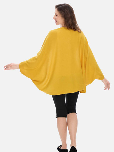 Woman wearing a yellow cashmere wrap and black leggings on a white background