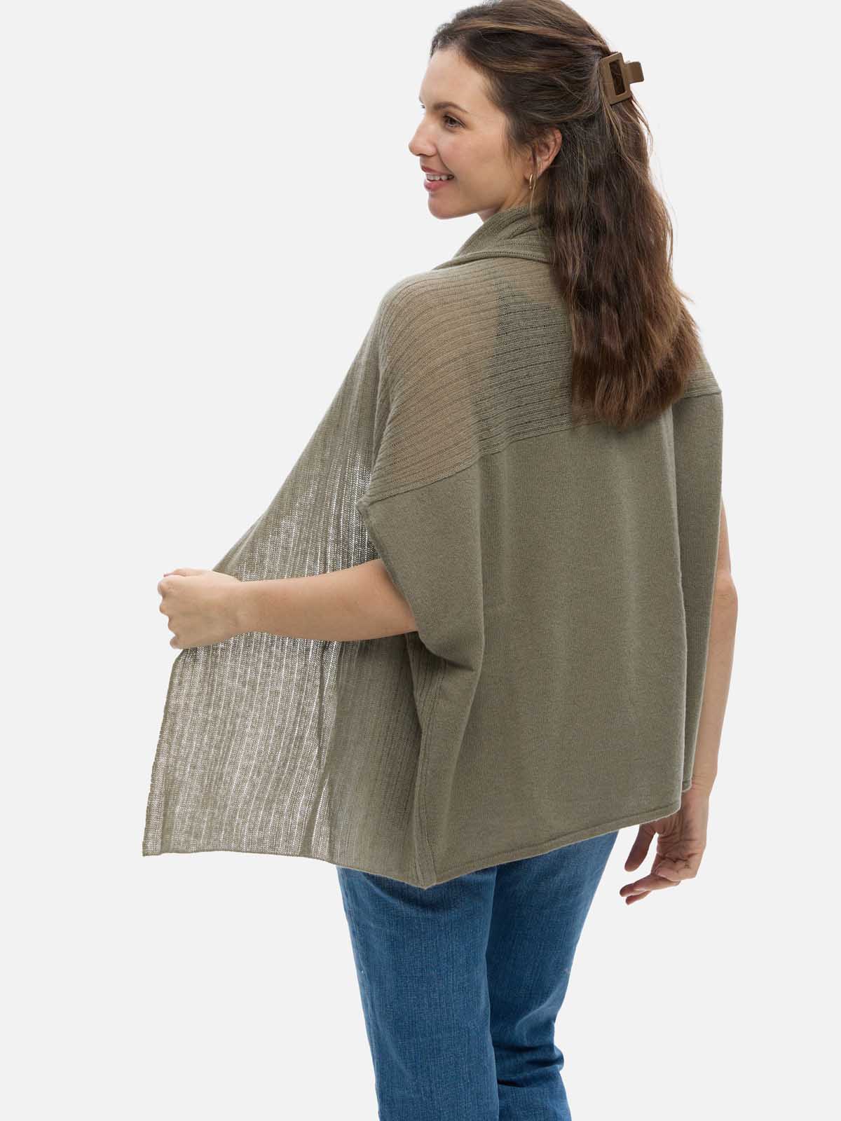Woman wearing a green cashmere vest over a plaid shirt on a white background