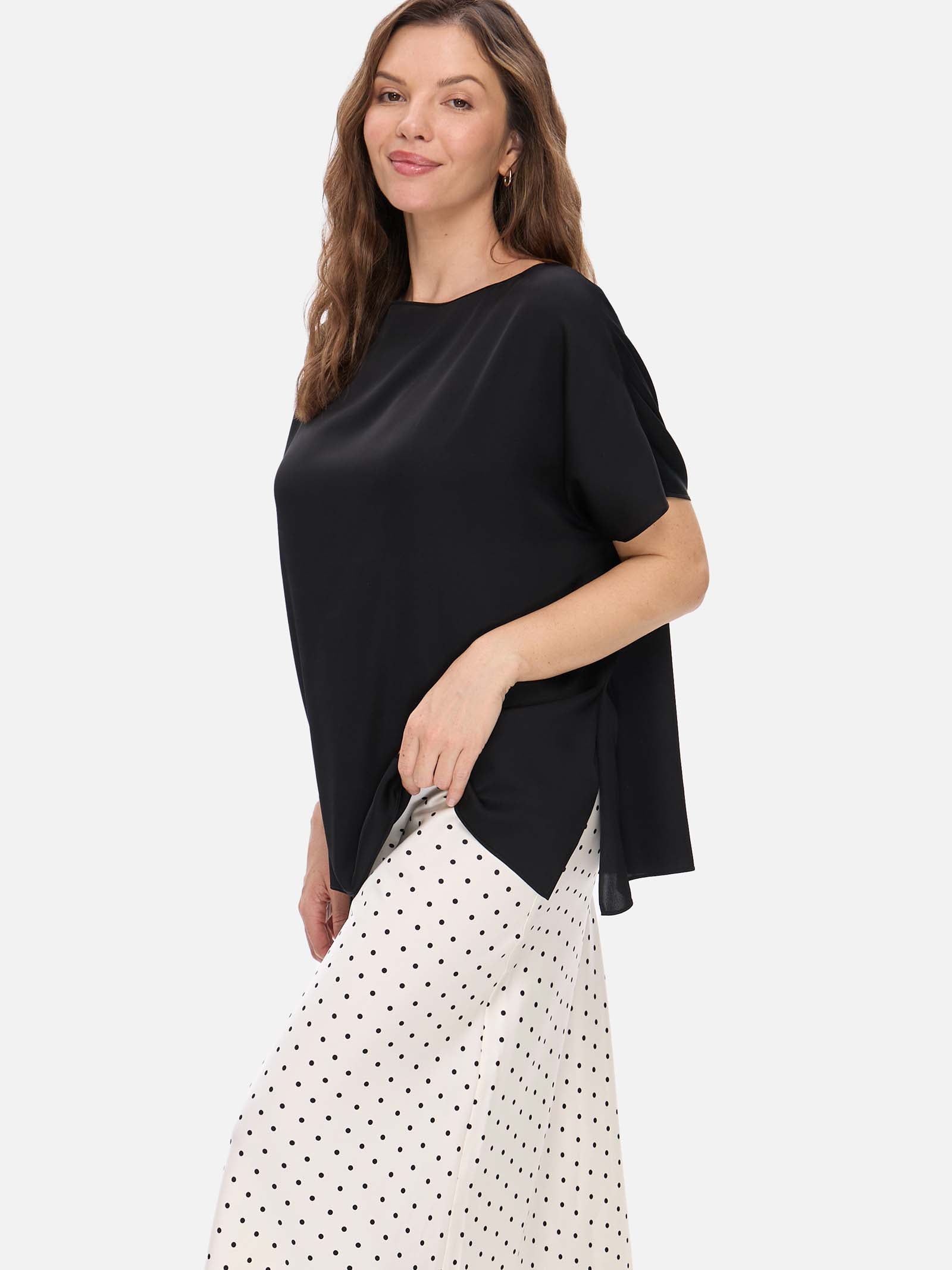 Woman wearing a black silk top and white polka dot skirt on a white background