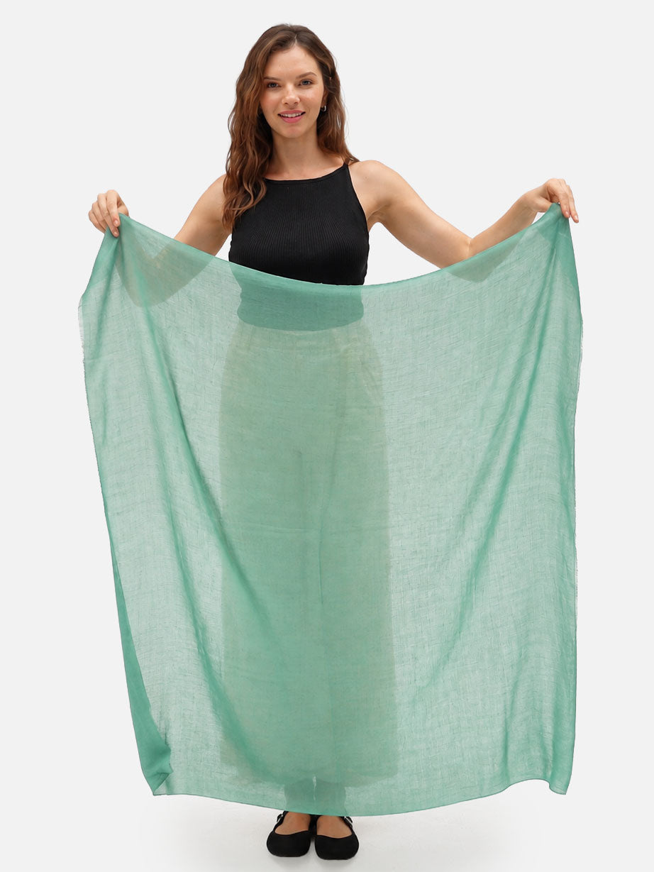 A woman holding a sage green cashmere scarf.