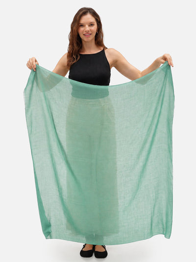 A woman holding a sage green cashmere scarf.
