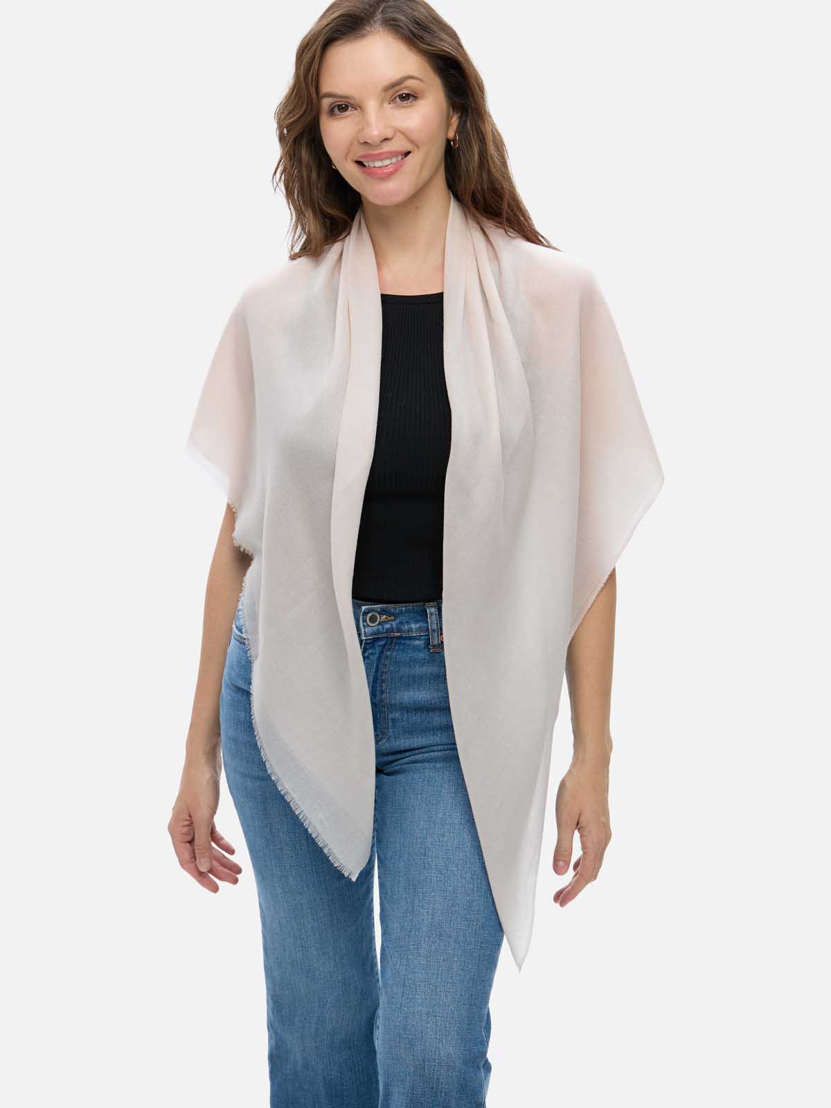Woman wearing an Ivory Square Featherlight Cashmere Scarf draped over her shoulders, styled with a black top and blue jeans.