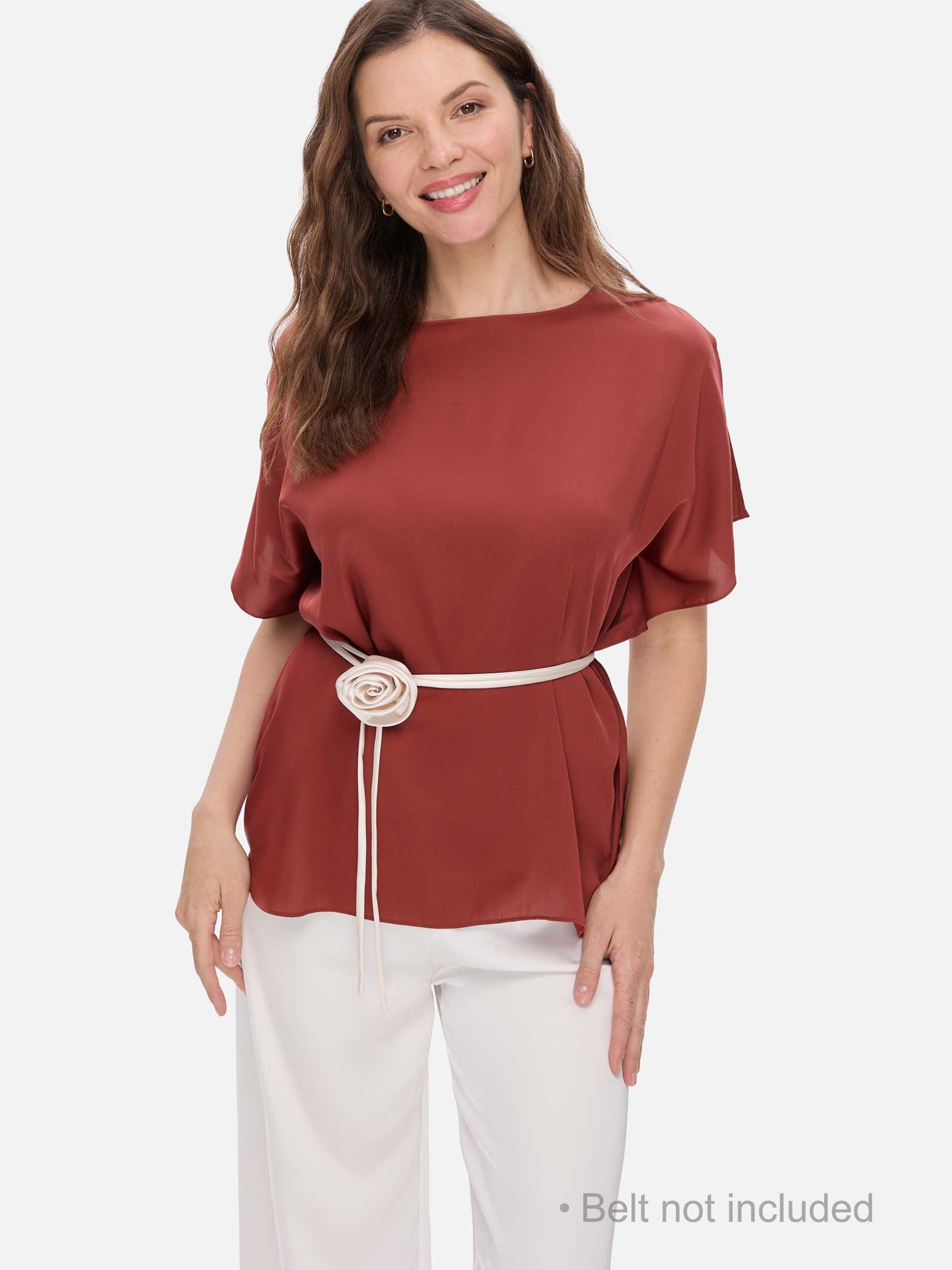 Woman wearing a clay red silk top with a belt on a white background