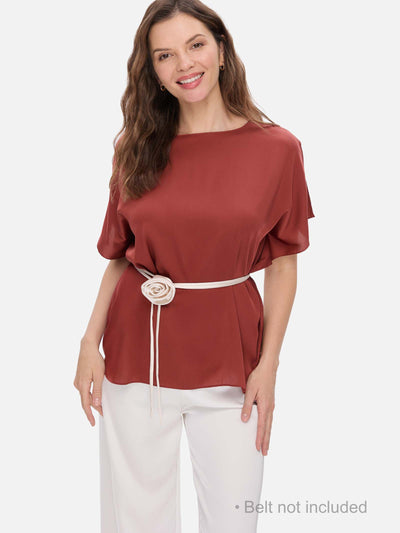 Woman wearing a clay red silk top with a belt on a white background