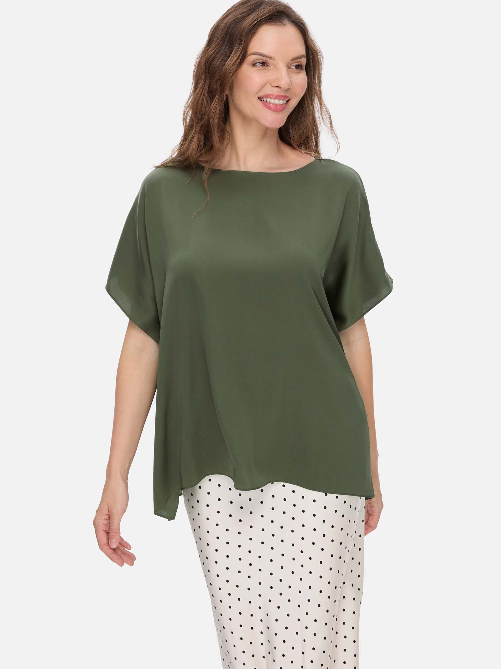 Woman wearing a green silk top and polka dot pants on a white background