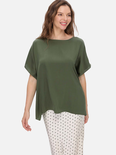 Woman wearing a green silk top and polka dot pants on a white background