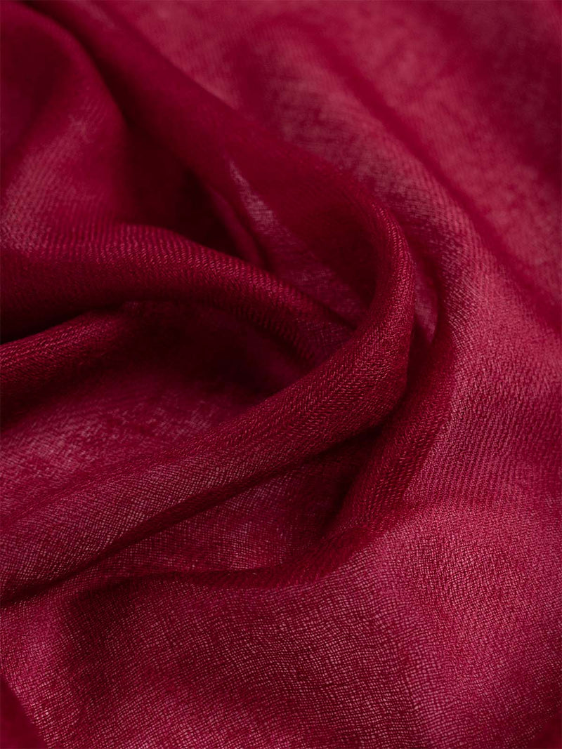 Woman wearing a wine red Ovcio Featherlight Cashmere Scarf over a white top and ivory trousers.