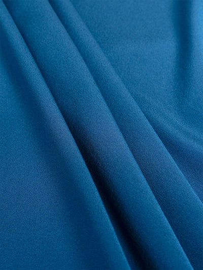 A close-up of draped blue silk fabric with soft folds and a smooth texture.