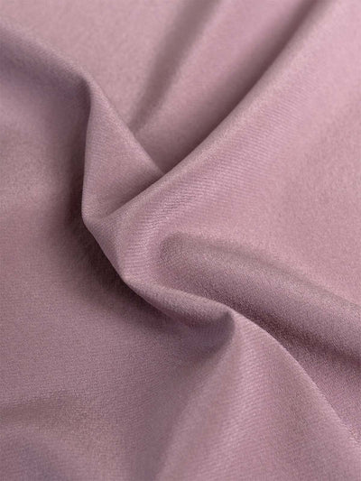 A close-up of draped mauve silk fabric with soft folds and a smooth texture.